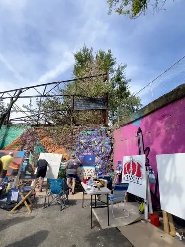 Artists bringing vibrant life and color to an outdoor mural event.